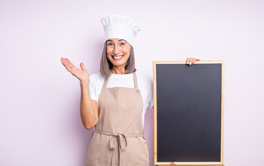 Wall Mural - senior pretty woman feeling happy, surprised realizing a solution or idea. chef and blackboard concept