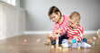 © candy1812 - Sister and brother playing with cubes together on the floor indoors.