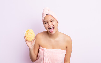 Wall Mural - hispanic pretty woman with cheerful and rebellious attitude, joking and sticking tongue out. bathrobe and sponge concept