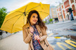 © Dragana Gordic - Rainy day asian woman wearing a raincoat outdoors. She is happy.She used her hand to touch the rain. The girl with a yellow umbrella costs in the rain.