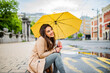 © Dragana Gordic - Good mood at any weather. Attractive young smiling woman carrying umbrella and adjusting her coat while walking by the street. The young woman smiles and laughs under the rain