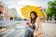 © Dragana Gordic - Good mood at any weather. Attractive young smiling woman carrying umbrella and adjusting her coat while walking by the street. The young woman smiles and laughs under the rain