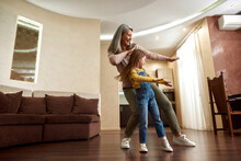 Middle-aged Woman And Young Girl Dancing At Home