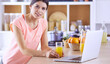 © lenets_tan - Young woman in kitchen with laptop computer looking recipes, smiling. Food blogger concept