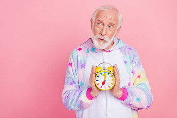 Poster - Portrait of attractive minded grey-haired man holding clock thinking copy space isolated over pink color background