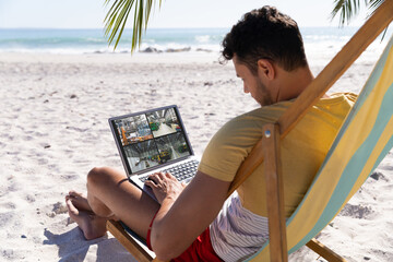 Sticker - Caucasian man on holidays using laptop with views of warehouse from security cameras on screen