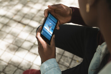 Canvas Print - African american man in park watching swimming competition on smartphone