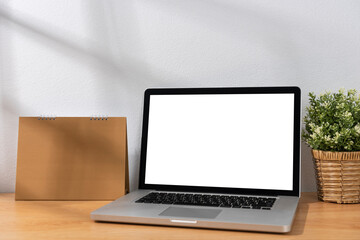 Wall Mural - Mockup Blank screen laptop computer and calendar on wood table with white wall background.