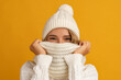 young smiling happy pretty blond woman wearing white knitted sweater, scarf and hat, warm winter cold season fashion accessories trend, posing on yellow studio background isolated