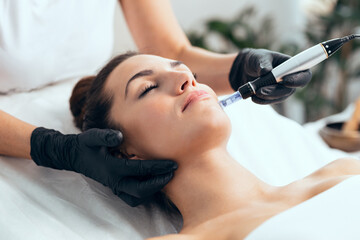 cosmetologist making mesotherapy injection with dermapen on face for rejuvenation on the spa center.