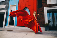 Young Gorgeous Woman In Long Red Dress Posing In Modern City