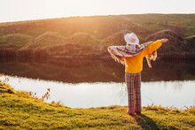 Back View Of Woman Relaxing By Autumn Lake At Sunset. Stylish Girl In Hat Admires Fall Landscape Wearing Warm Clothes