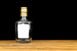 Mockup label on empty glass bottle of whiskey, cognac or vodka on a black background, wooden table. Template, copy space photo