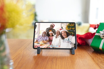 Poster - Happy african american family in santa hats smiling on tablet video call screen at christmas time