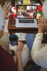 Poster - Two waving men making laptop christmas group video call with four smiling caucasian women