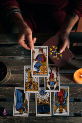 Close-up of a fortune teller displaying some tarot cards on a wooden table