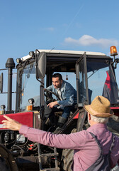 Poster - Two farmers talking beside tractor in field