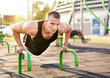© PEOPLEVISUALS - Millennial athletic muscular sportsman doing push ups in a fitness park outdoors - Focused male doing workout on the floor - Strength and bodybuilding concept