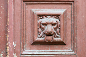 fragment of an old wooden door with a bas-relief of a fearsome lion's head