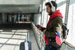 © NFstock - Close up view of the traveler man wearing headphones looking at the smartphone screen while listening music and waiting for his flight. Citizens and american symbols concept concept