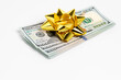 Cash gift of 100 dollar bills with gold bow. Gift tax, charitable donation and holiday present concept.