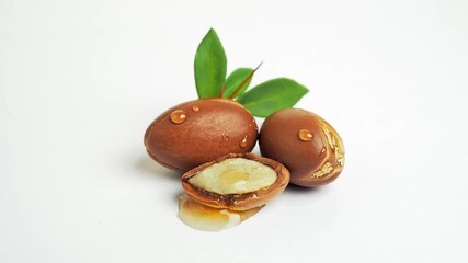 Wall Mural - Argan nuts with green leaves on white background. 