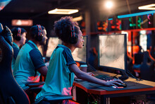 Rear view of concentrated addicted multiethnic gamers using powerful computers for online game while sitting in computer club