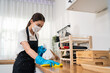 © Kawee - Asian active cleaning service woman worker cleaning in kitchen at home.