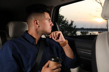 Wall Mural - Thoughtful man with cup of drink in modern taxi