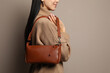 © New Africa - Fashionable young woman with stylish bag on beige background, closeup. Space for text