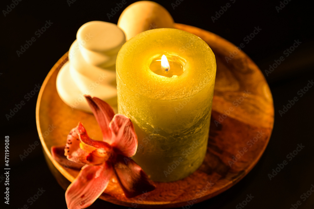 Tray with spa stones, candle and flower on dark background