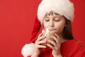 Wall Mural - Little girl drinking hot cocoa on color background