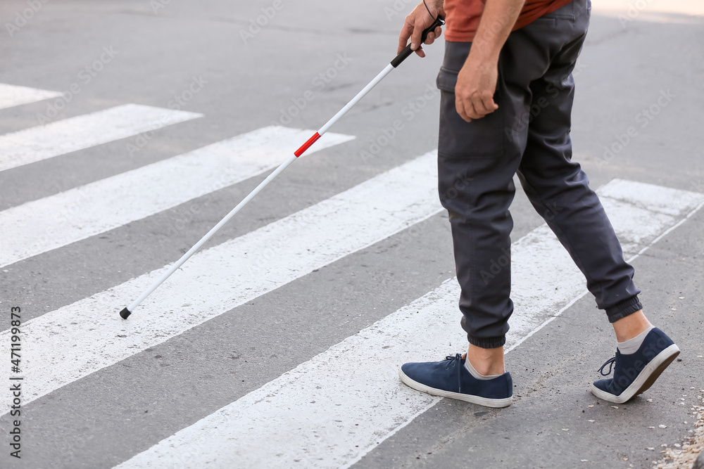 Blind senior man crossing road in city