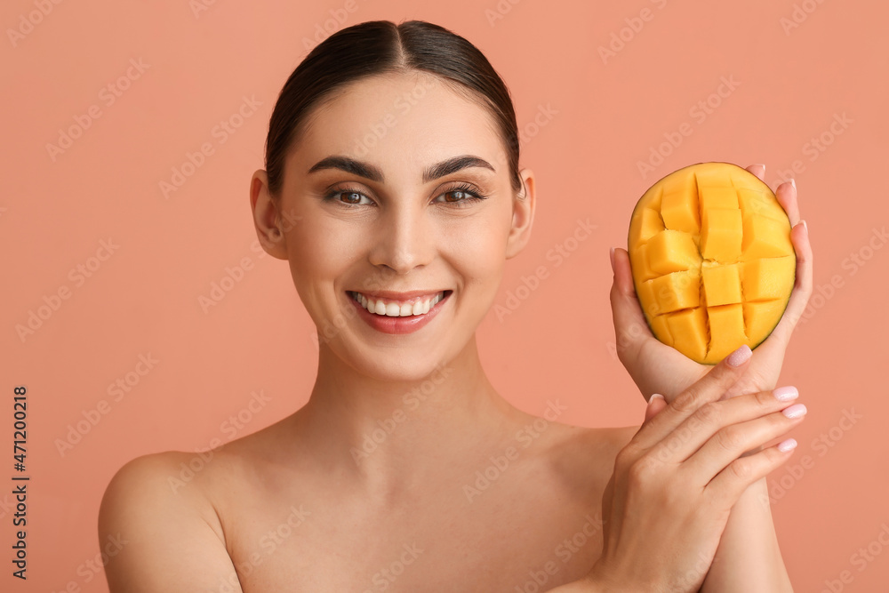 Beautiful smiling woman holding cut mango on color background