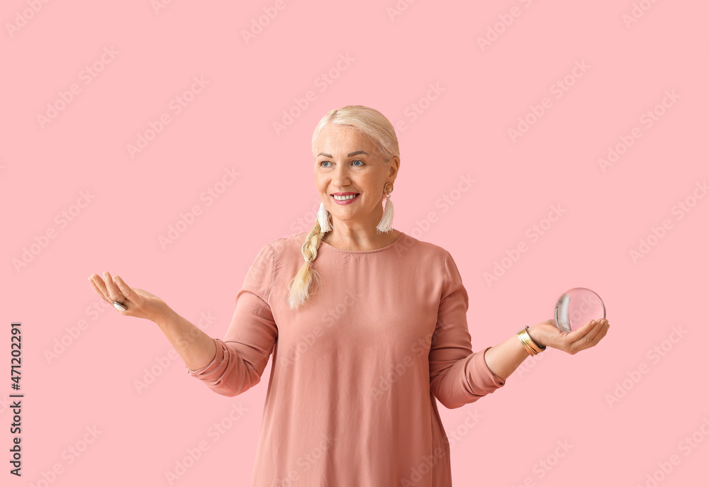 Mature woman with crystal ball on color background