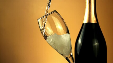 Wall Mural - Stream of champagne pours into a glass of air bubbles. On a yellow background.Filmed is slow motion 1000 frames per second. High quality FullHD footage