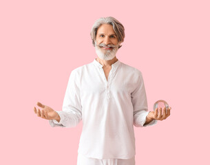 Mature man with crystal ball on color background