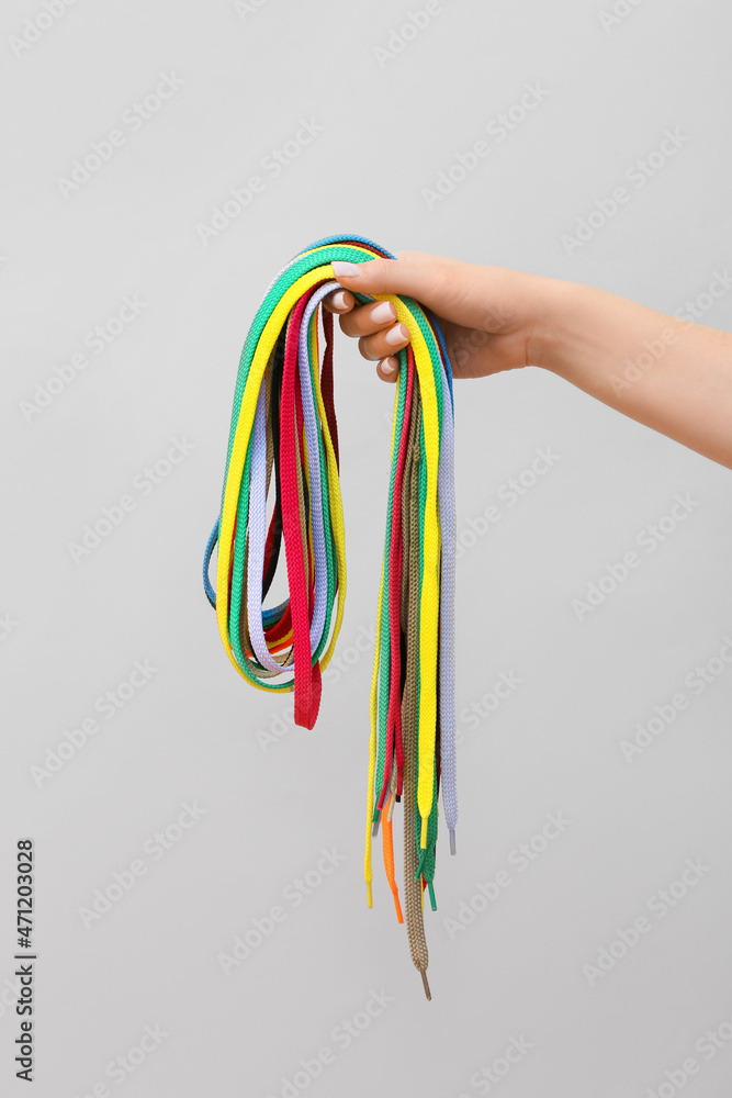 Woman holding many shoe laces on white background, closeup