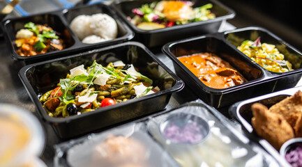 Open and closed plastic disposable takeaway containers with various food ready for deliveries as takeaways surge in coronavirus pandemic