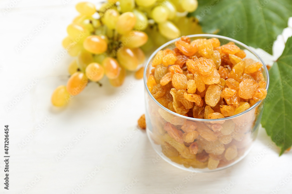 Glass bowl with tasty raisins on light table, closeup