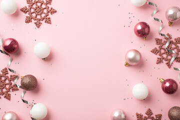 Top view photo of pink and white christmas tree balls pink snowflakes silver serpentine and sequins on isolated pastel pink background with copyspace