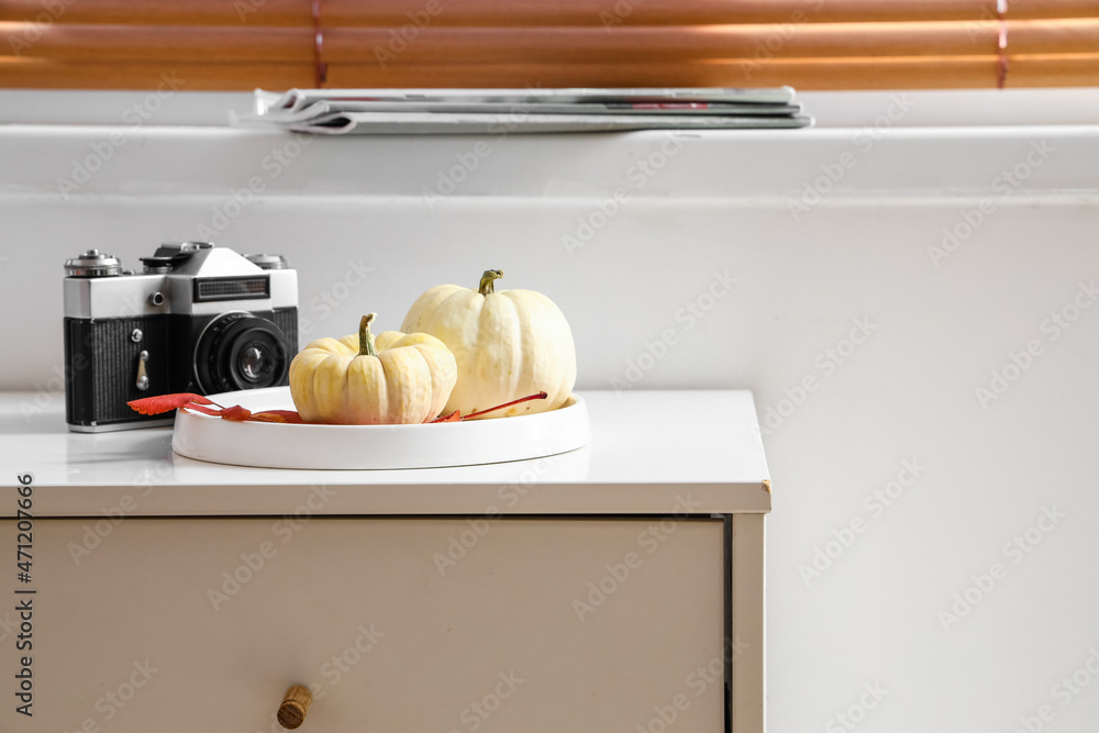 Tray with pumpkins and photo camera on table