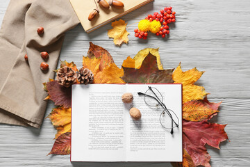 Wall Mural - Composition with open book, eyeglasses and beautiful autumn decor on light wooden background