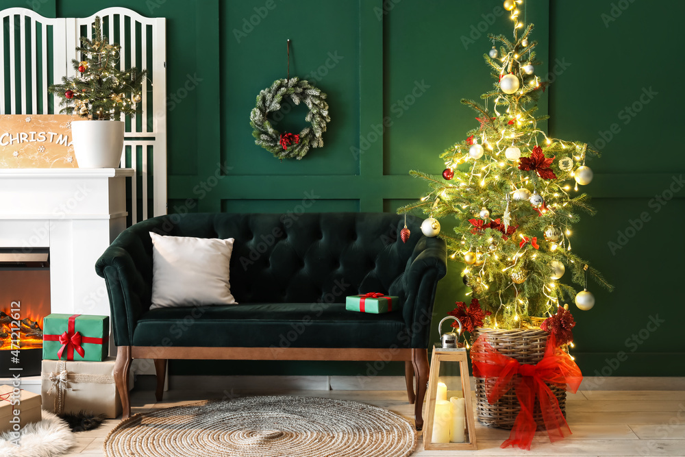 Interior of stylish living room with green sofa, Christmas tree and glowing lights