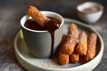 Wall Mural - Traditional spanish dessert churros - fried choux pastry with chocolate sauce on a plate .