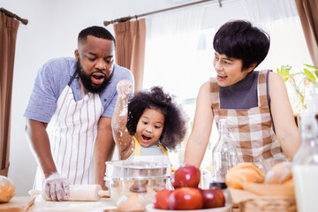 Happy African American father and daughter having fun while preparing cookie dough at home. happy family time.