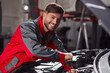 Smiling technician fixing car engine