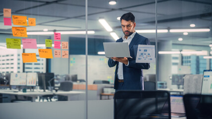 Leinwandbilder - Young Confident Businessman Using Laptop Computer in Modern Office. Stylish Manager in a Suit Working on Commercial, Financial and Marketing Projects. Sales Specialist Browsing Internet, Emails.