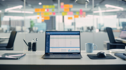 Leinwandbilder - Laptop Computer with Financial Analytical Spreadsheet Application Standing on the Desk in the Modern Creative Office. In the Background Glass Wall with Colorful Planning Notes.