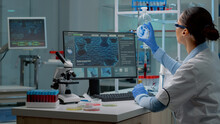 Innovation Scientist Studying Petri Dish With Liquid Bacteria While Using Modern Computer With Cell Animation In Laboratory. Woman With Lab Coat And Glasses Doing Pharmaceutical Research